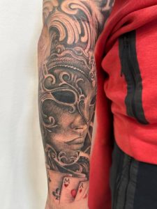 Black and grey realistična tetovaža venecijanske maske na podlaktici